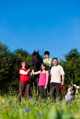 Family with children posing with a horse, one child riding the animal