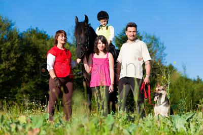 Family with children posing with a horse, one child riding the animal